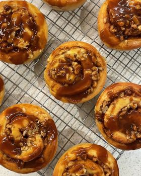 Caramel pecan brioche rolls glazed with caramel on a wire cooling rack