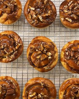 Rows of caramel pecan brioche rolls on a wire cooling rack, seen from above