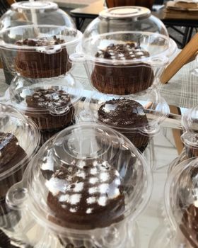 Packaged chocolate fondants with GM stickers stacked in clear boxes on a market tray