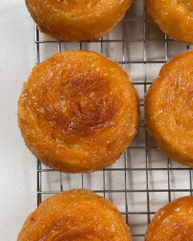 Caramelised kouign amann pastries with swirled tops cooling on a wire rack