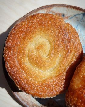 Close-up of a caramelised swirled kouign amann on a ceramic plate