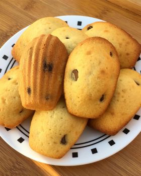 A pile of vanilla and chocolate chip madeleines on a black and white patterned plate