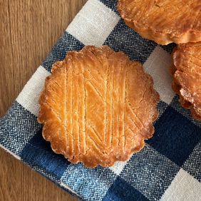 Two gâteaux bretons with a crosshatched top on a blue and white checked cloth