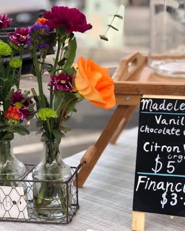 Flowers in glass bottles and a chalkboard price list on the market table at the Redlands Morning Farmers Market