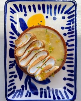 A lemon meringue tart with toasted meringue on a blue and white patterned plate